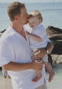 A portrait of father kissing his baby is an important professional family events photography moment.