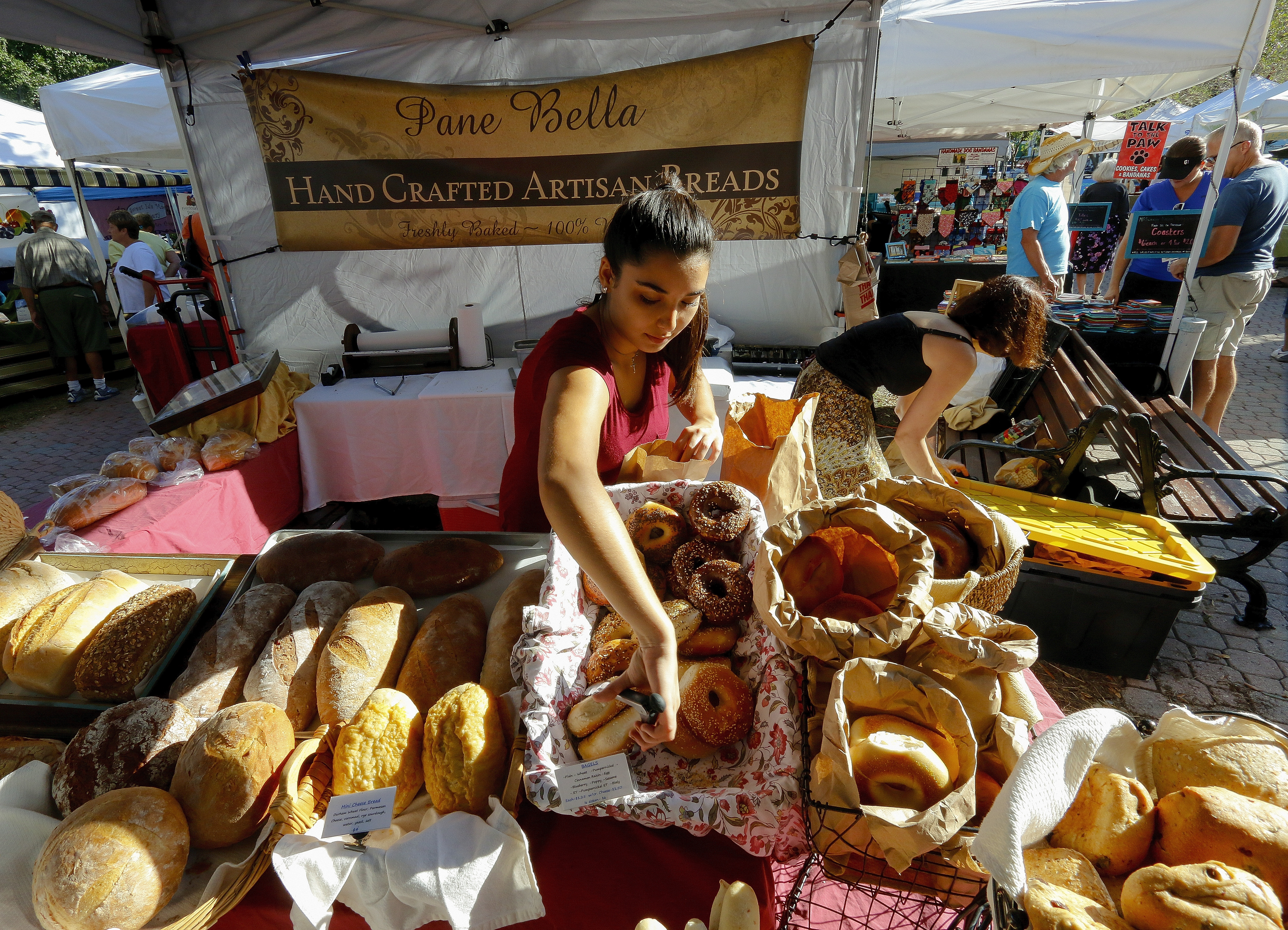 Therese Galante removes bagels from the loaves of bread on display by Pane Bella at the Tampa Bay Farmers' Market
